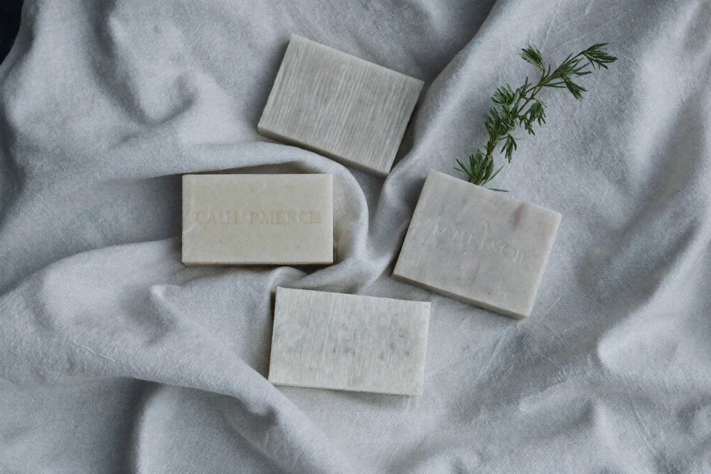 Three bars of handmade soap on rumpled linen, overhead