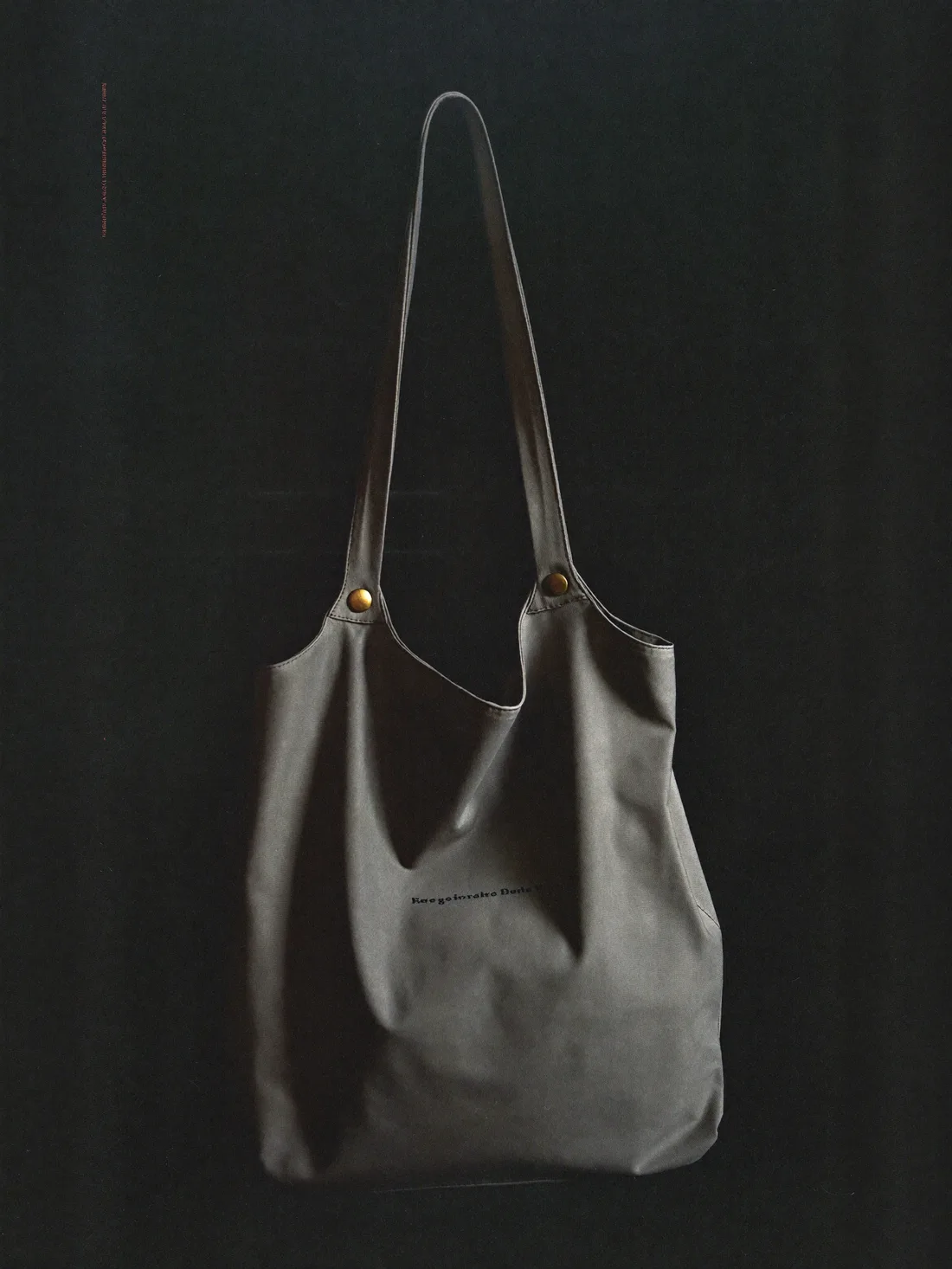 Waxed canvas tote with brass rivets against a dark ground